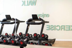 A gym with treadmills and a rack of dumbbells.