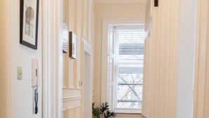 A hallway with white walls, a radiator, a framed picture, and a potted plant. - The Devonshire Suite - Your 5 Star West End Stay! (Glasgow)