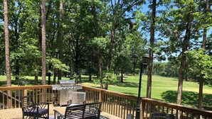 Eine Terrasse mit Gartenmöbeln, einem Grill und Blick auf einen Golfplatz.