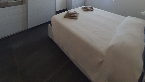 A hotel room with a bed, a nightstand, a mirror, and a window with curtains. - Ana&julio holiday home (Valledoria)