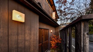 Un bâtiment en bois, avec une enseigne, une porte et un arbre aux feuilles d’automne.