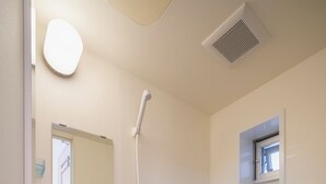 A modern bathroom with a bathtub, a shower, a mirror, and a window. - Casa Leo Asato (Naha)