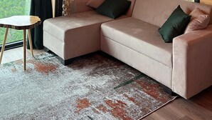Een knus interieur met een houten plafond, een bakstenen muur, een comfortabele bank met kussens en een kleine tafel.