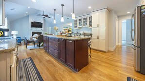 Een moderne keuken met een centraal eiland, houten vloer en hanglampen.
