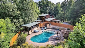 Ein zweigeschossiges Haus mit Swimmingpool, umgeben von einer Holzterrasse und einem überdachten Patio.