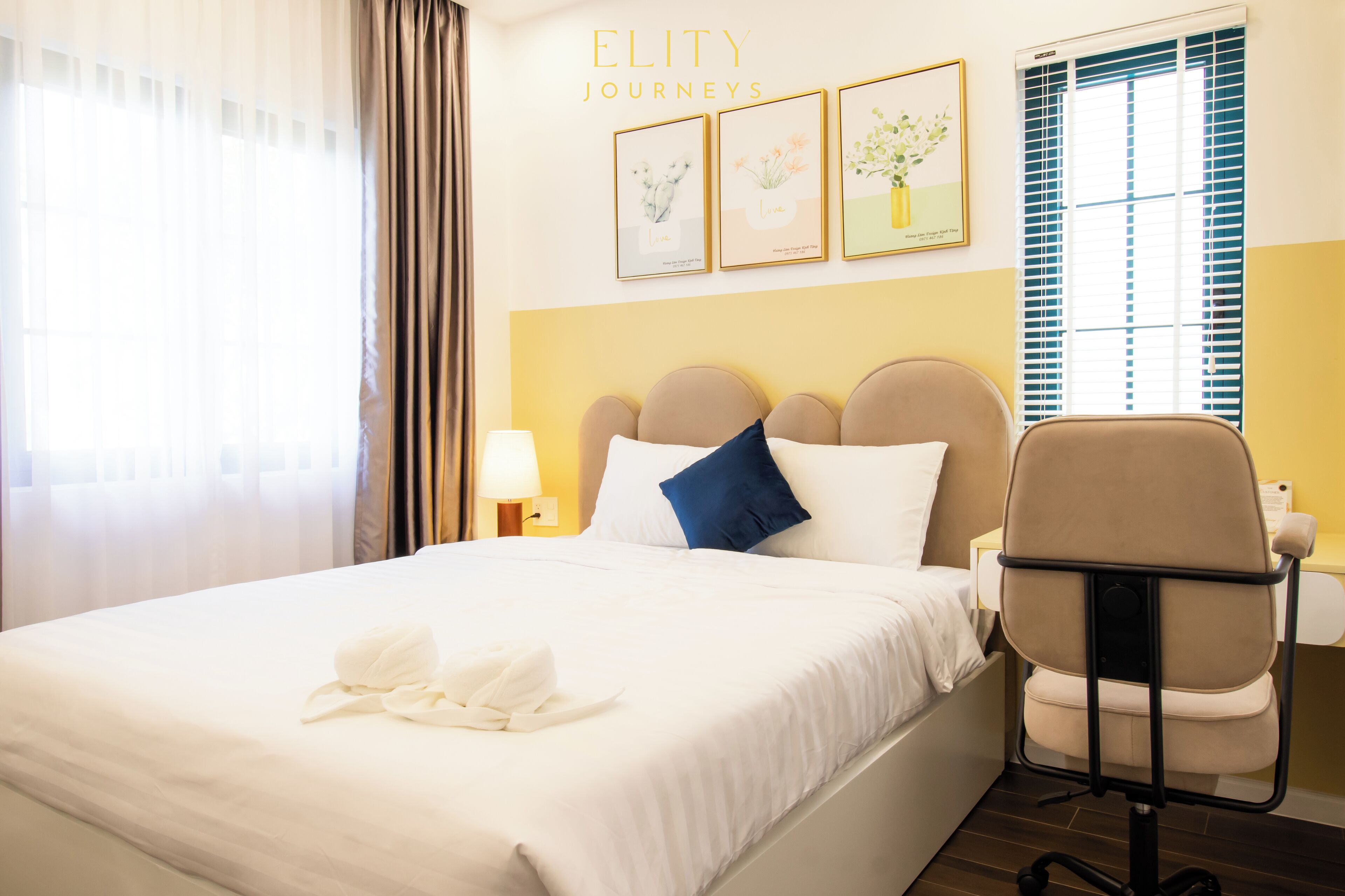 Una camera d'albergo con un letto, una sedia, un comodino con una lampada e quadri appesi al muro.