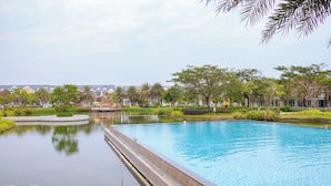 A swimming pool with a water feature, surrounded by greenery and buildings. - Villa Novaworld Phan Thiet - Elity (Tien Thanh)