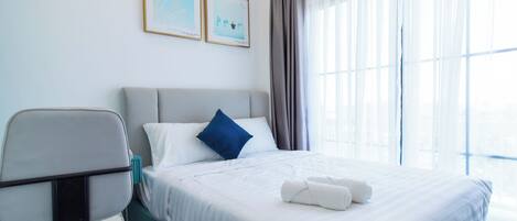 A hotel room with a bed, a chair, and two framed pictures on the wall.