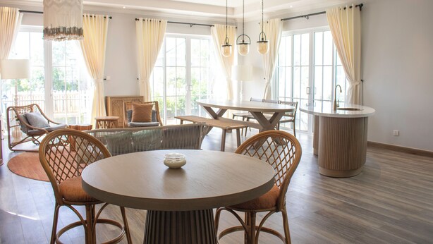 A spacious room with a round dining table, wicker chairs, and a central light fixture. - Villa Novaworld Phan Thiet - Elity (Tien Thanh)