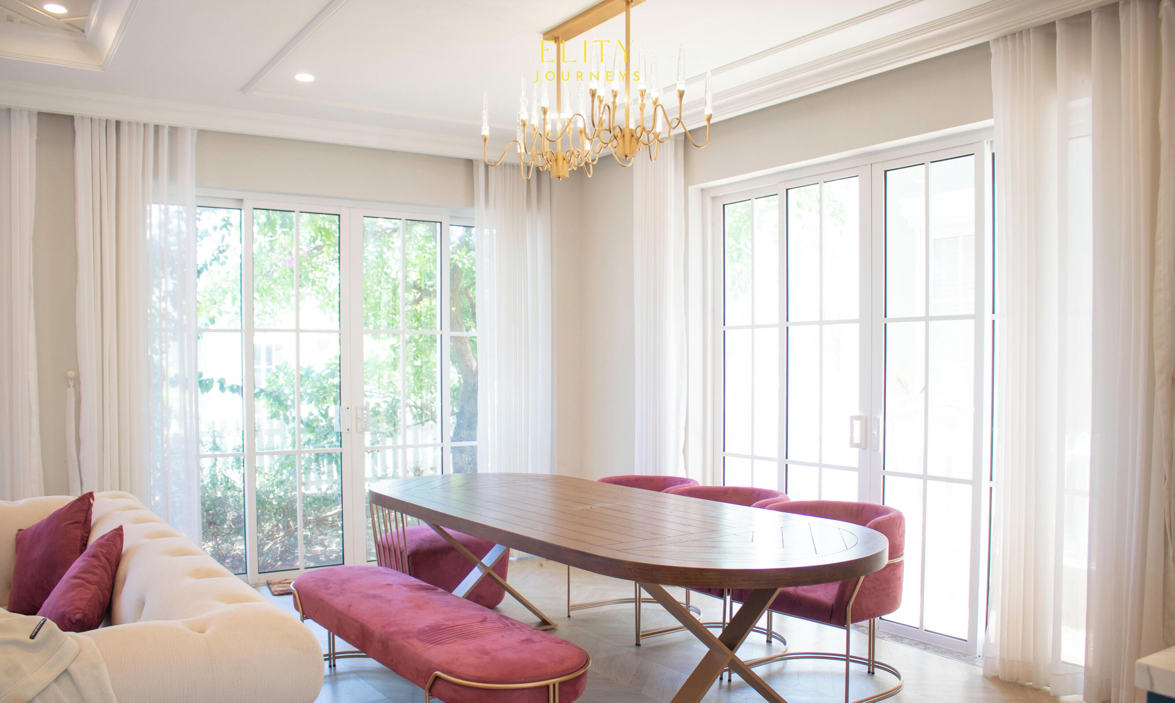 A spacious room with a large dining table, comfortable seating, and large windows allowing natural light.