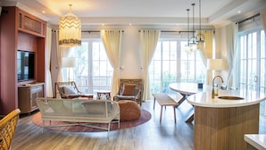 A spacious living area with a round wooden coffee table, wicker furniture, and a large window with curtains. - Villa Novaworld Phan Thiet - Elity (Tien Thanh)