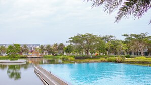 A swimming pool with a water feature, surrounded by greenery and buildings. - Villa Novaworld Phan Thiet - Elity (Tien Thanh)