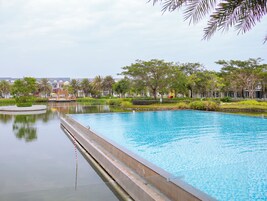 Una piscina con fuente acuática, rodeada de follaje y edificios.