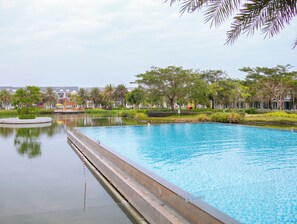 A swimming pool with a water feature, surrounded by greenery and buildings. - Villa Novaworld Phan Thiet - Elity (Tien Thanh)