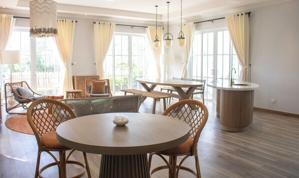 A spacious room with a round dining table, wicker chairs, and a central light fixture. - Villa Novaworld Phan Thiet - Elity (Tien Thanh)