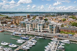 A marina with boats docked, a modern building complex with multiple floors, and a waterfront view.