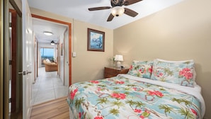 A bedroom with a bed, a ceiling fan, a nightstand, a lamp, and a framed picture on the wall. - Summer Deal Updated 2BR Kona Condo Near Ocean and Downtown Kona (Kailua-Kona)