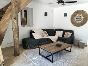 Una sala de estar moderna con un sofá negro, una mesa de centro de madera y un espejo decorativo en la pared.