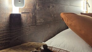 Un dormitorio moderno con cabecera de madera, una mesita de noche y una cama con dos almohadas.