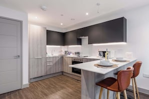 A modern kitchen with a central island, built-in appliances, and a minimalist design. - Little Sea - Moments from Waterfront Restaurants (Poole)