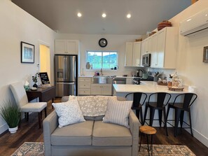 A modern kitchen with white cabinets, stainless steel appliances, and a large window. - Cozy Avon Country Escape (Deary)