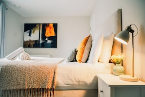 A neatly made bed with a blanket, pillows, a lamp, and a vase with flowers on a bedside table. - 3 Huntingdon Place (Edinburgh)