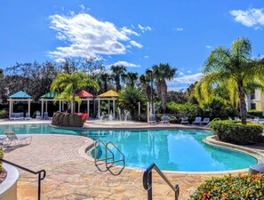 A swimming pool with lounge chairs and a gazebo. - Elegant 2Bd Condo Near Disney (Kissimmee)