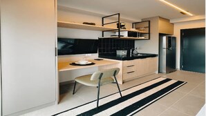 Una cuina moderna amb escriptori integrat, una cadira i un refrigerador.
