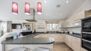 A modern kitchen with a curved island, stainless steel appliances, and pendant lighting.