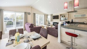 A modern living room with a dining area, a kitchen, and a balcony.