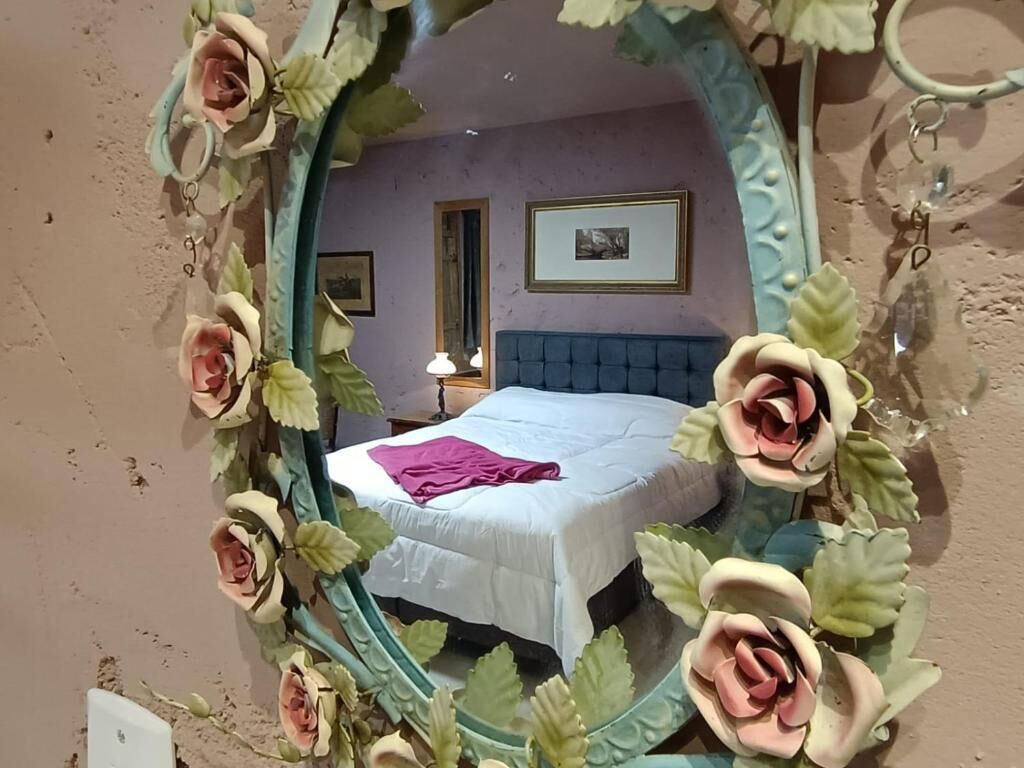 A bedroom with a bed, a nightstand, and a mirror with floral decorations.