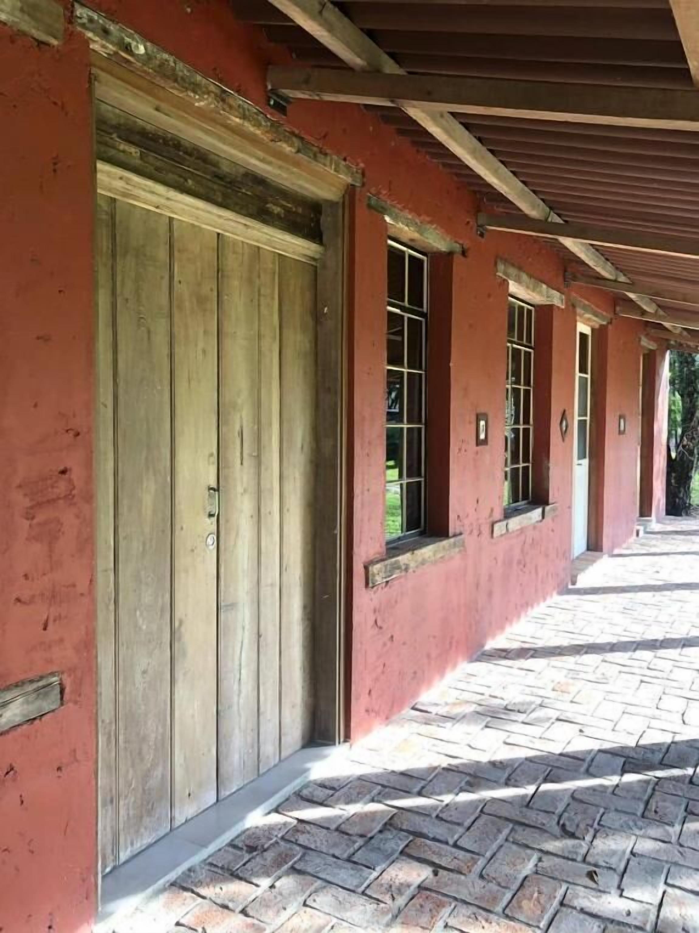 A corridor with red walls and wooden doors, leading to individual rooms.
