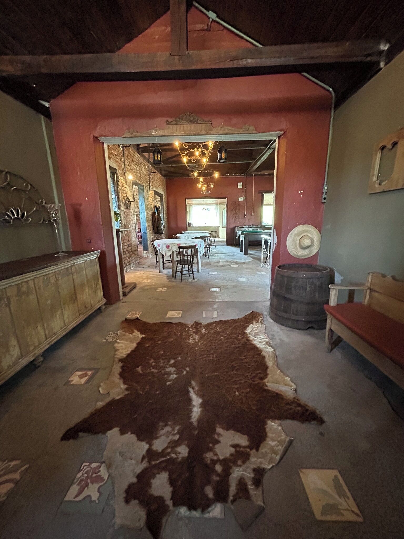 A rustic interior with a large cowhide rug, wooden furniture, and a billiards table.