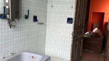Un baño con bañera, ducha e inodoro. Una puerta de madera da paso a otra habitación.