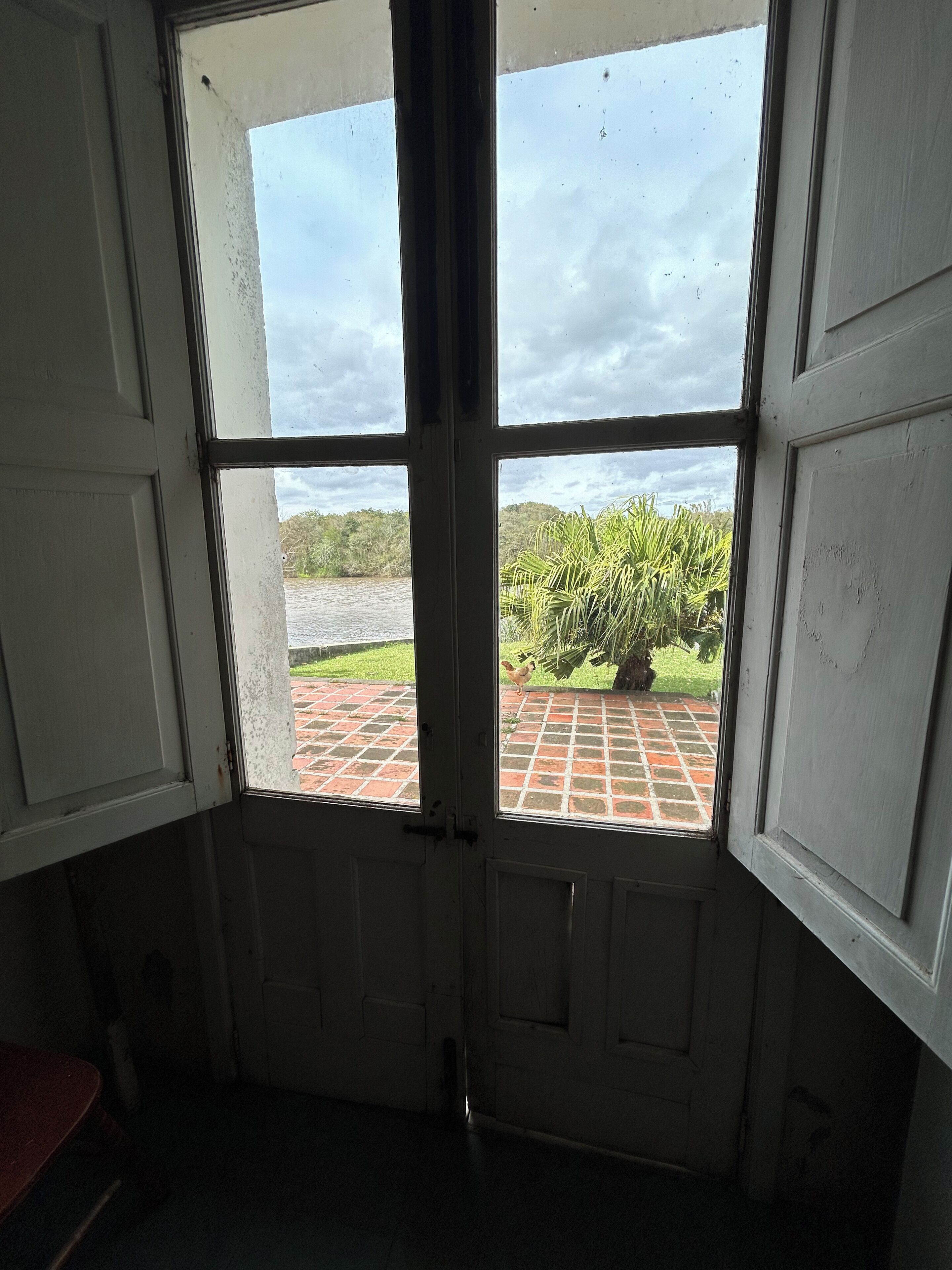 A room with a window overlooking a brick patio and greenery.