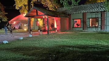 A building with a covered outdoor seating area, a tiled roof, and a well-maintained lawn.