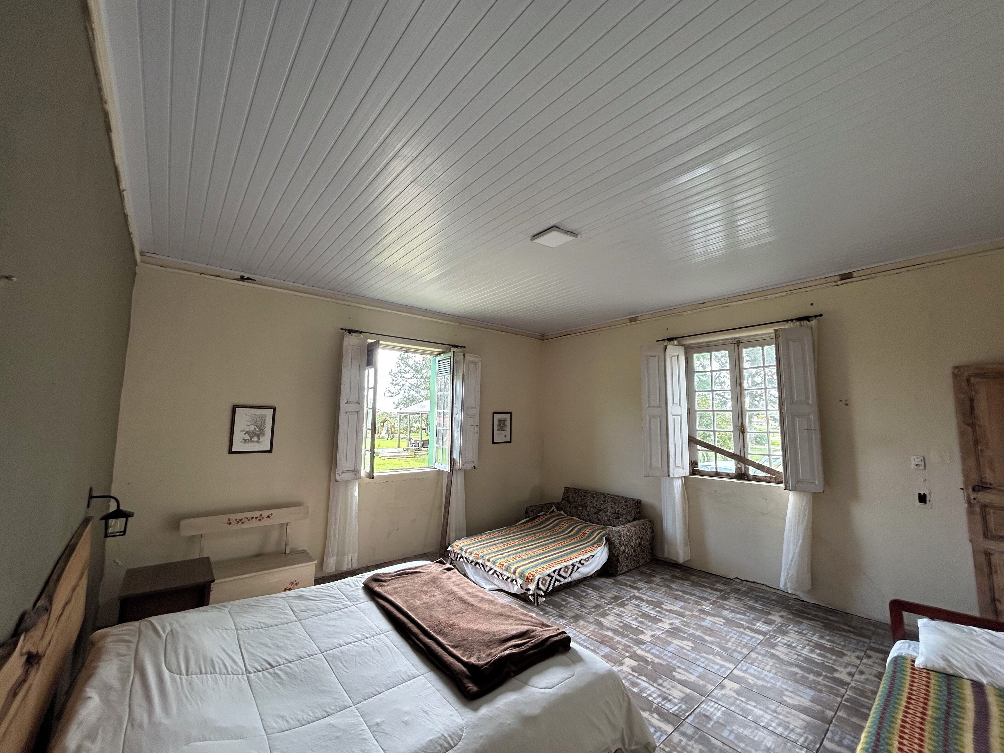 A room with two beds, a bench, and a window.