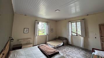 A room with two beds, a bench, and a window.