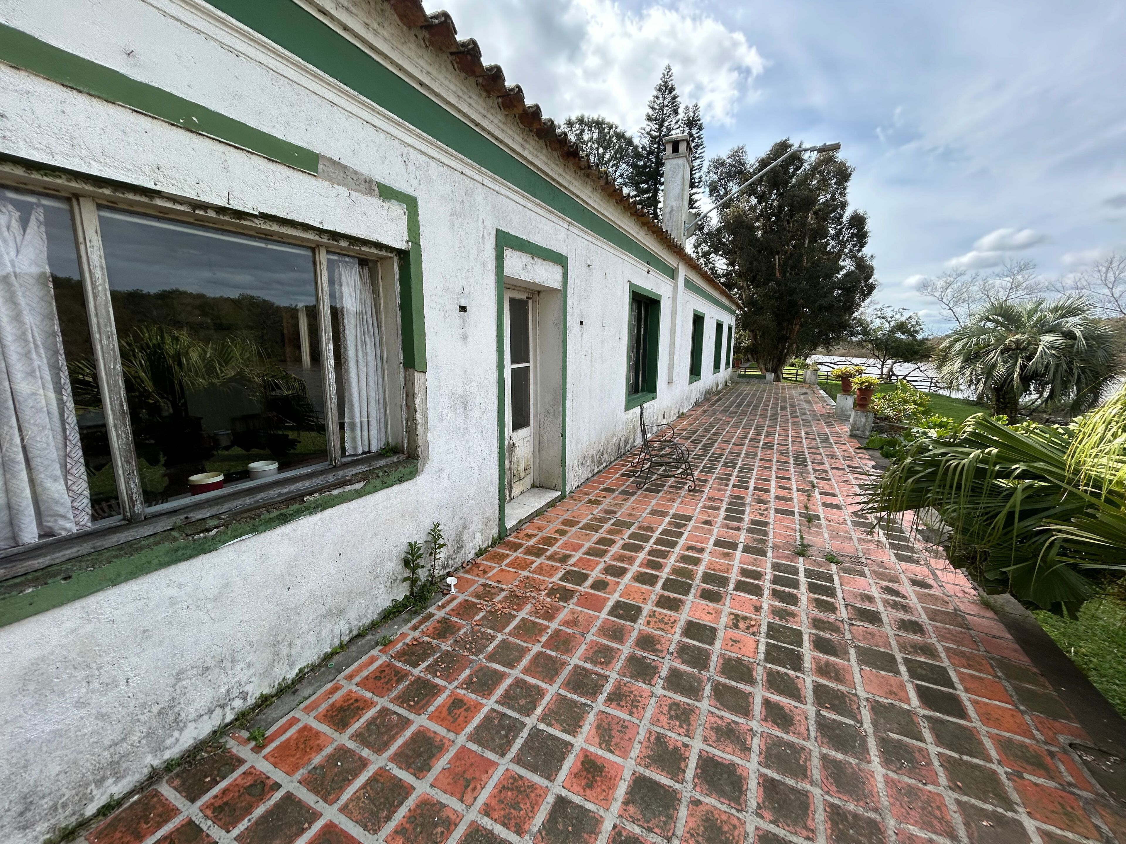 Um edifício com um caminho de tijolos que leva a uma fachada branca com detalhes verdes.
