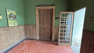 Una habitación con puerta de madera, suelo de baldosas y pared verde.