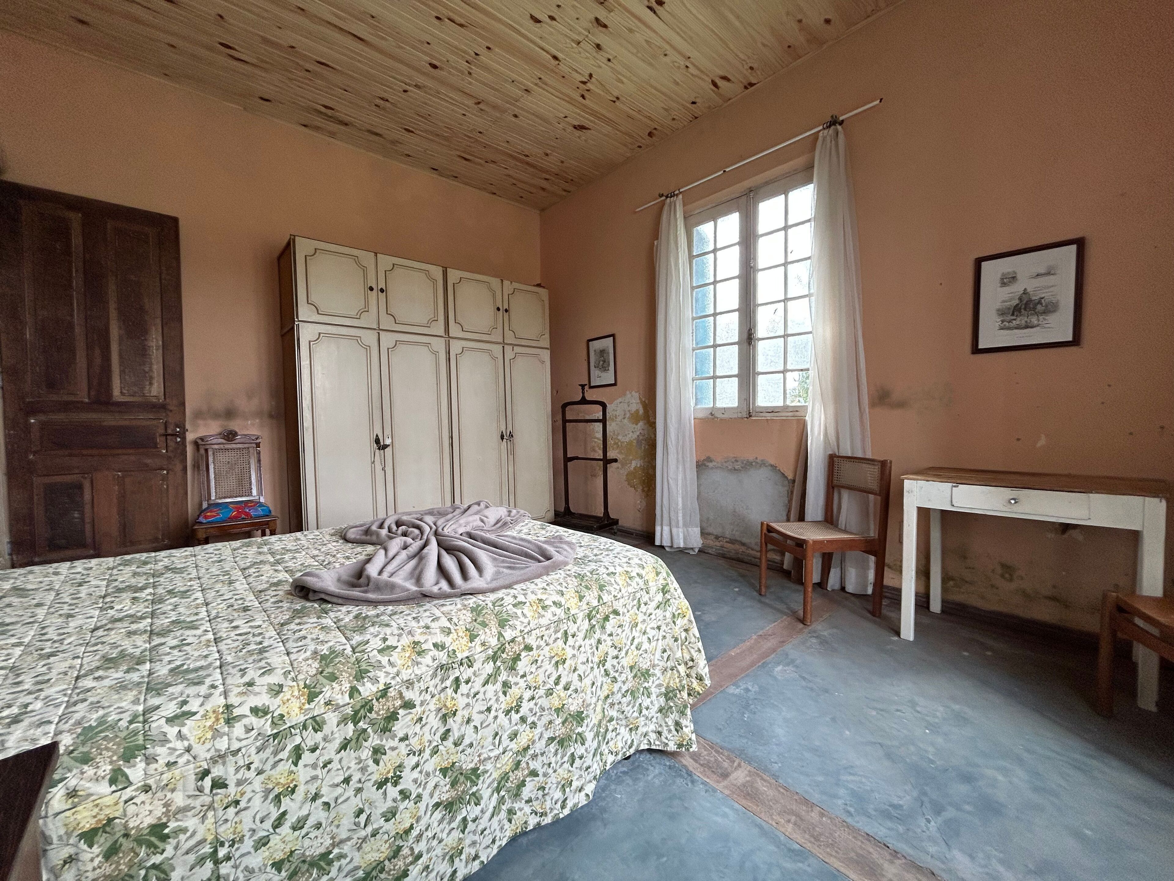 A bedroom with a bed, wardrobe, desk, and chair.