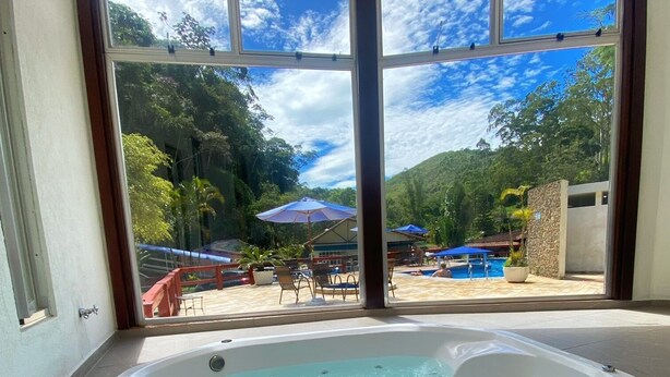Un jacuzzi con vista a un área de piscina y mobiliario exterior.