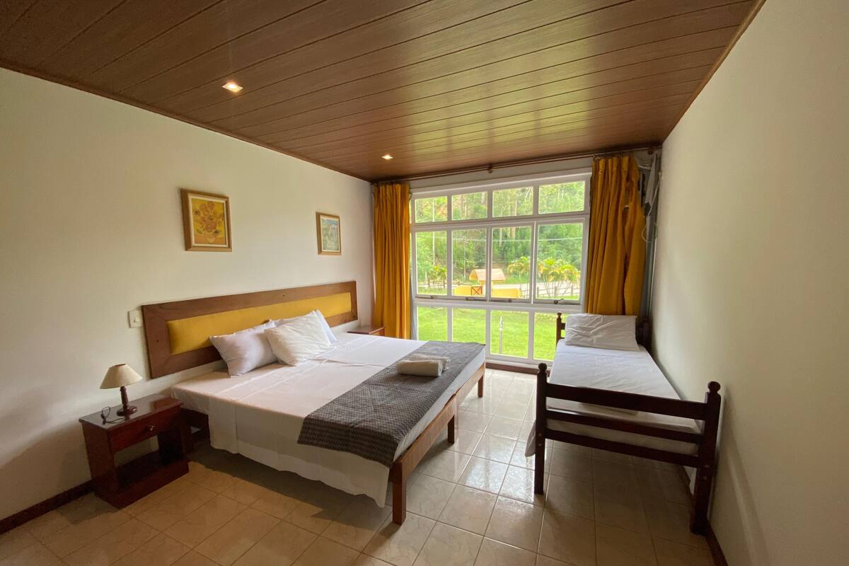 A hotel room with a bed, bedside table, lamp, and a window with curtains.