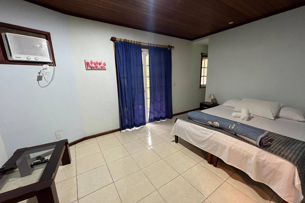 A bedroom with a bed, a desk, and a window with blue curtains.