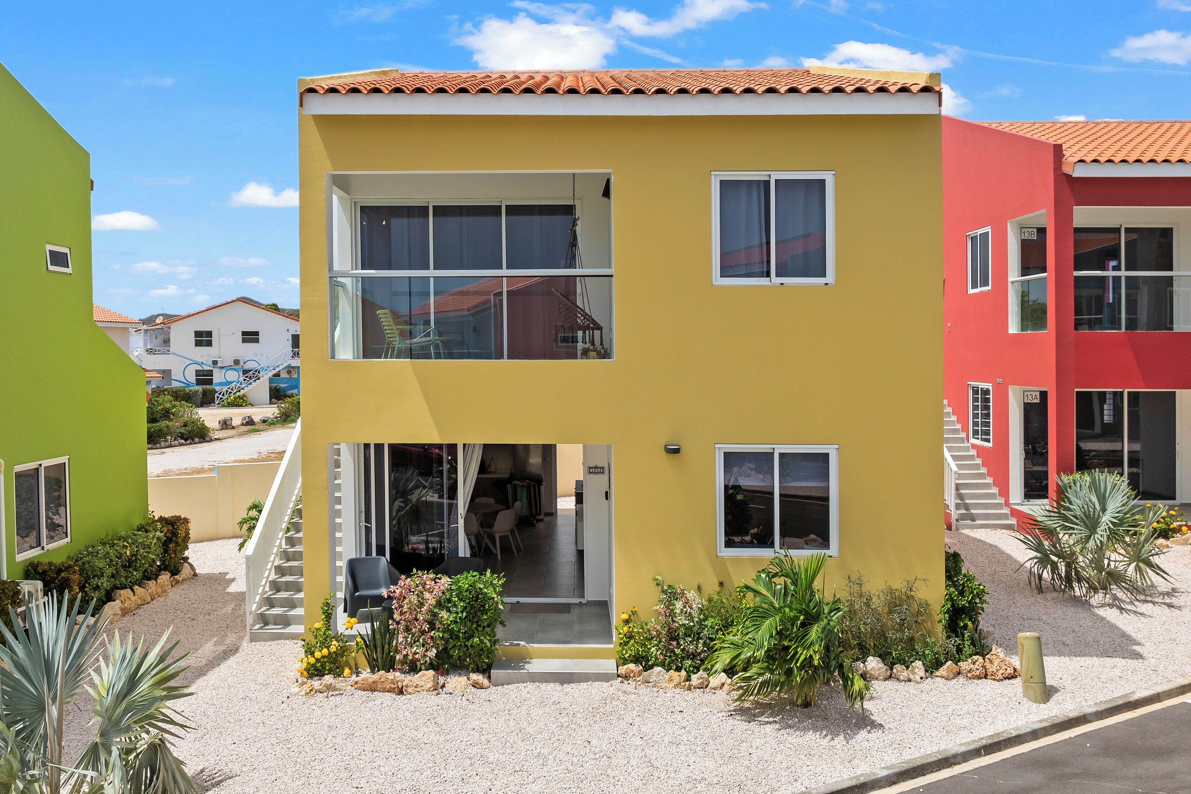 A two-story building with a yellow facade, white windows, and a red roof.