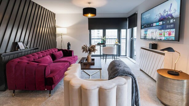 Una sala de estar moderna con un sofá modular, una mesa de centro y un televisor montado en la pared.