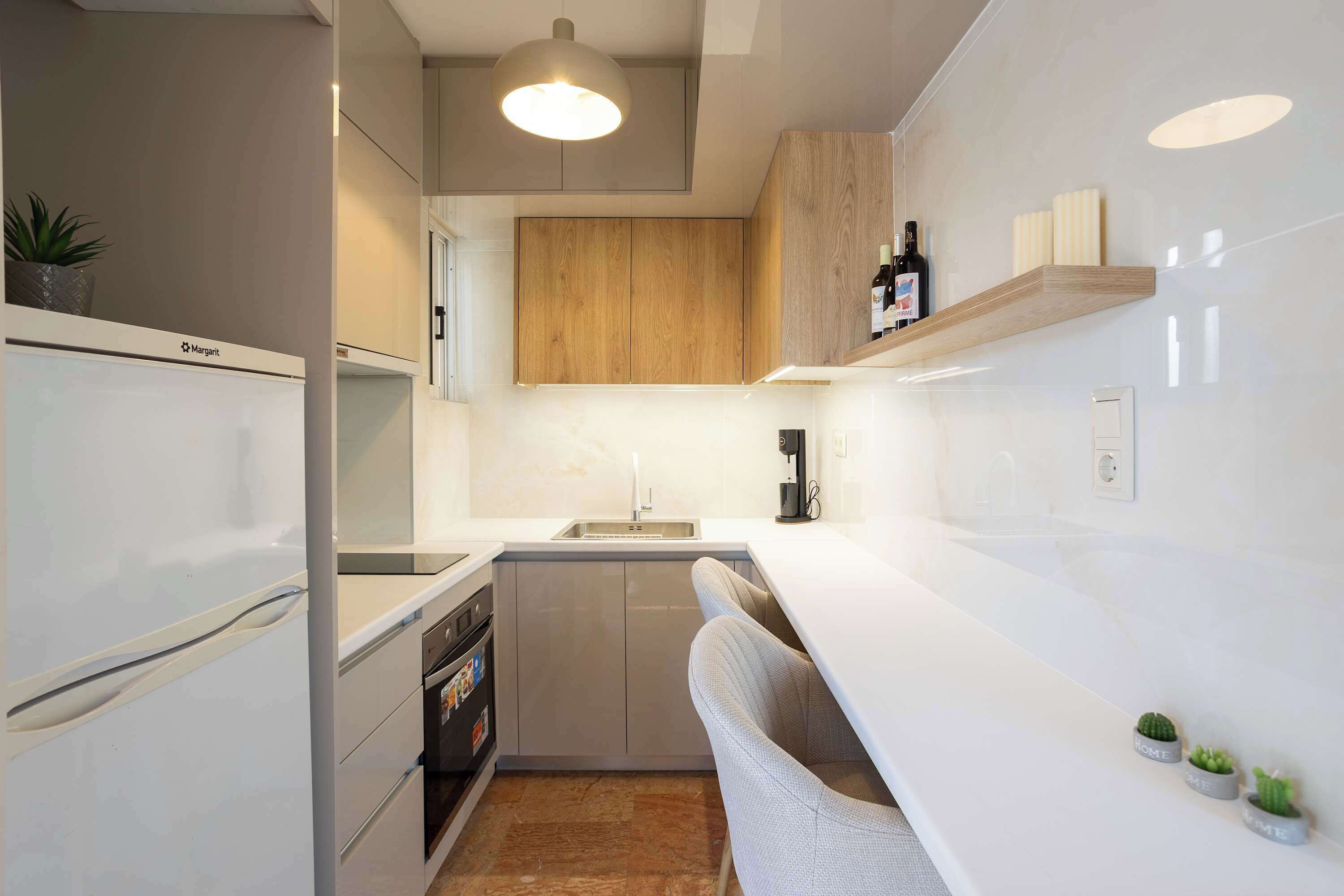 A modern kitchen with white cabinetry, a built-in oven, a sink, and a wooden upper cabinet.