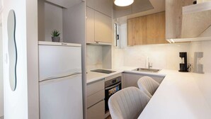 Cocina moderna con armarios blancos, horno empotrado, pileta y una pequeña planta en maceta sobre la encimera.