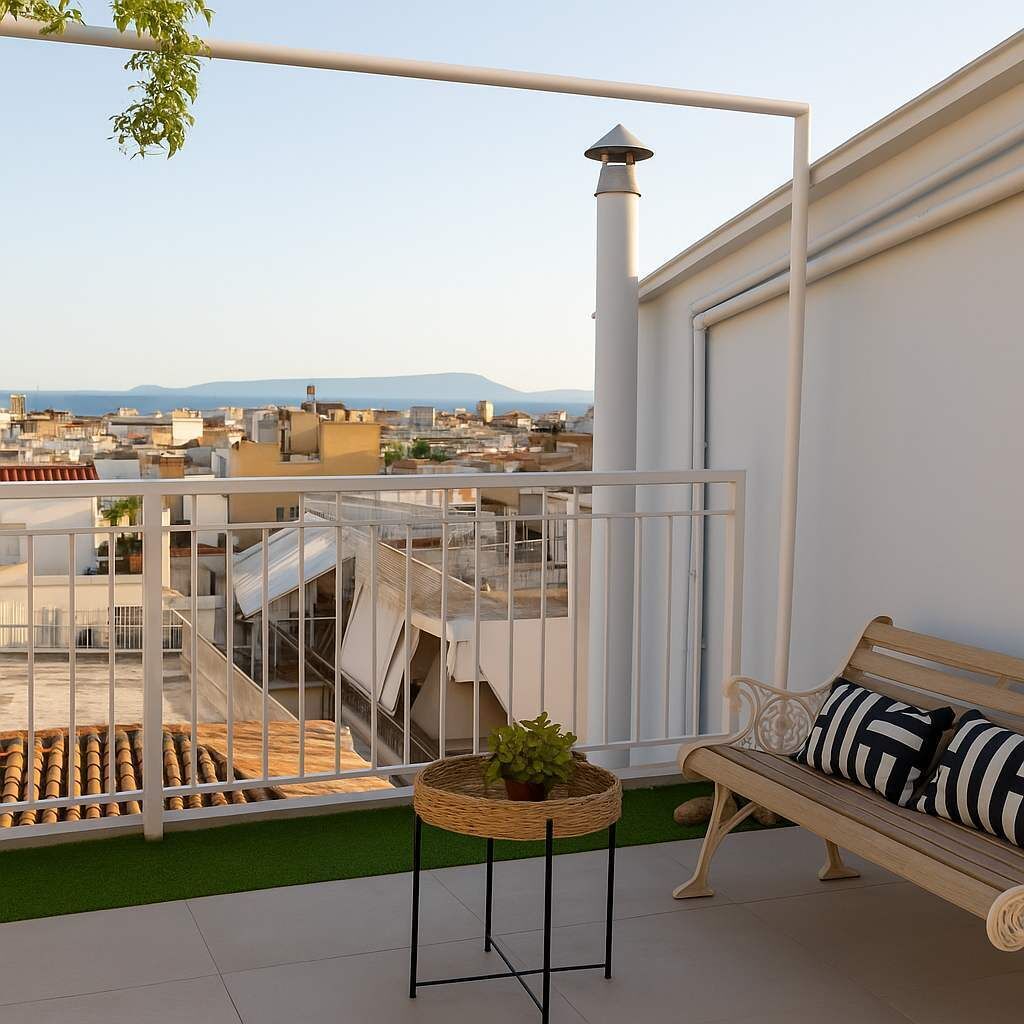 Una terraza en la azotea con barandilla de metal blanco, un banco de madera con cojines a rayas y una mesita redonda con una planta.