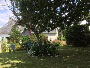A garden with a lawn, a chair, and a house with a sloped roof. - House with garden and terrace on the seafront. Quiet, at the start of the GR34. (Crozon)